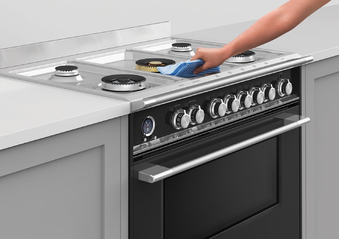 Hand wiping the cooktop of a dual fuel pyrolytic cooker