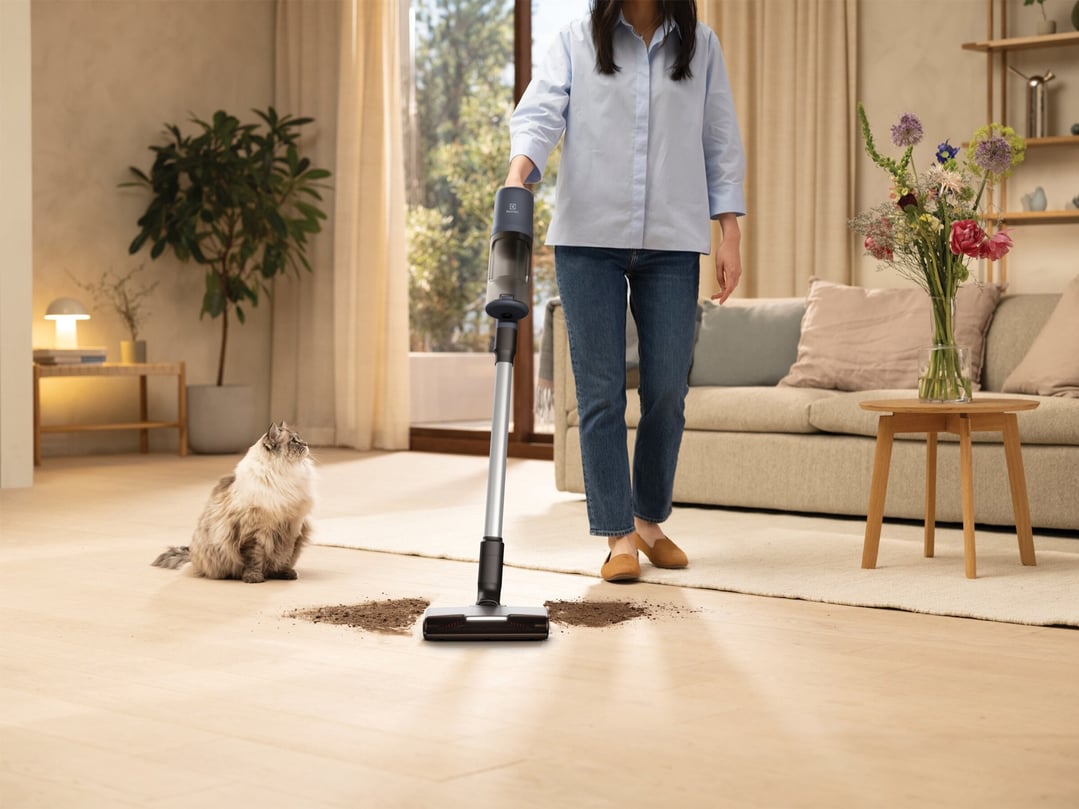 Woman using a cordless vacuum cleaner to clean dirt on a wooden floor