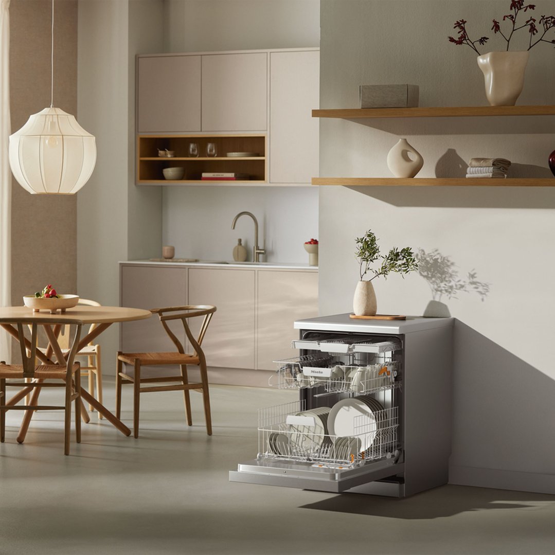 Freestanding dishwasher with door open in a modern kitchen and dining area