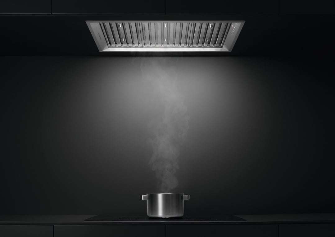 A rangehood above a pot of boiling water on a cooktop