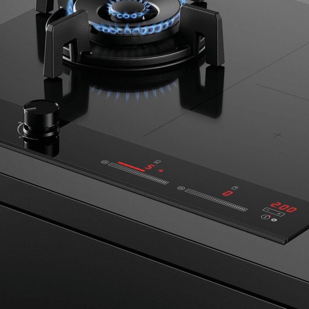 Close up of a cooktop with a gas burner lit and digital controls