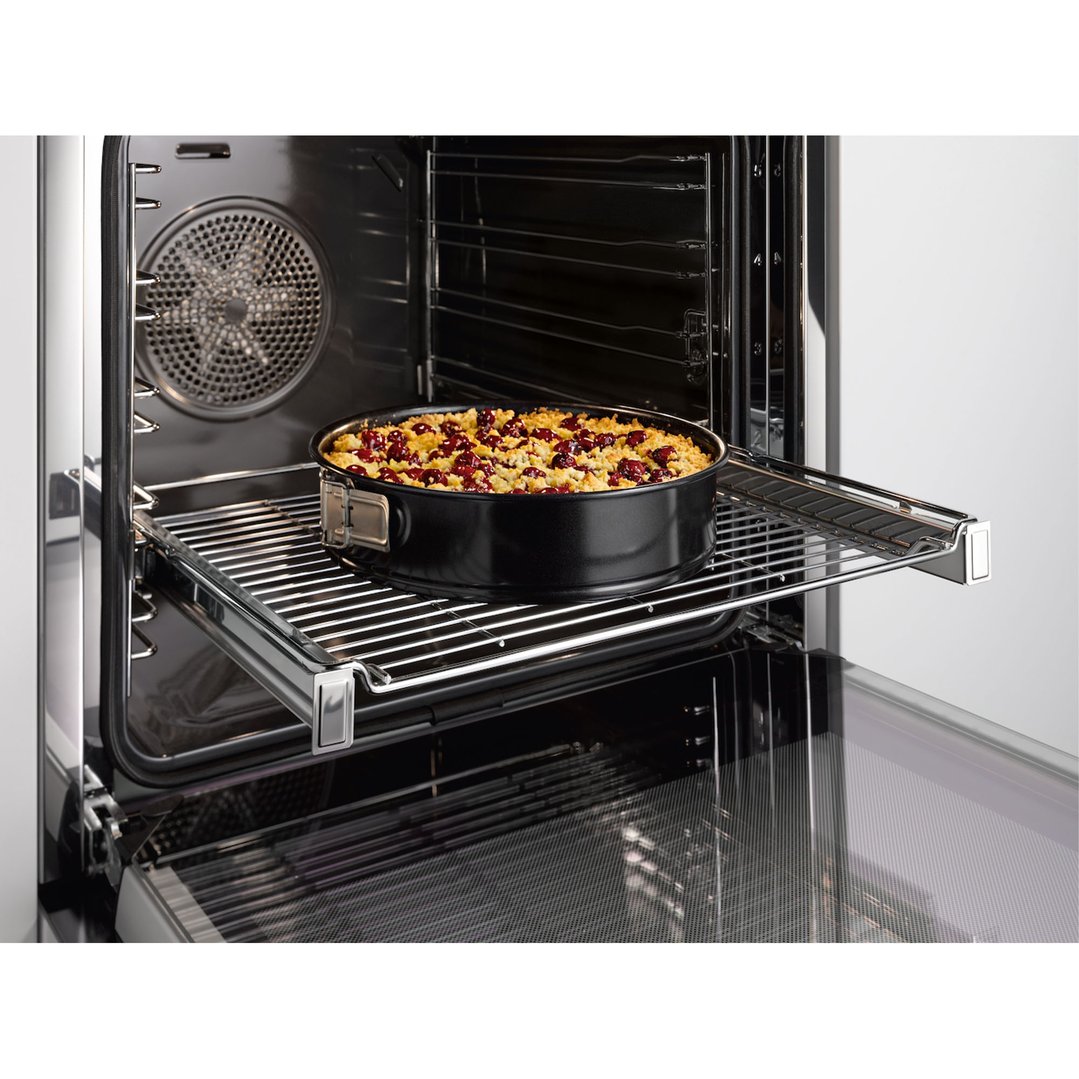 A cake in a springform pan on a rack in an open oven