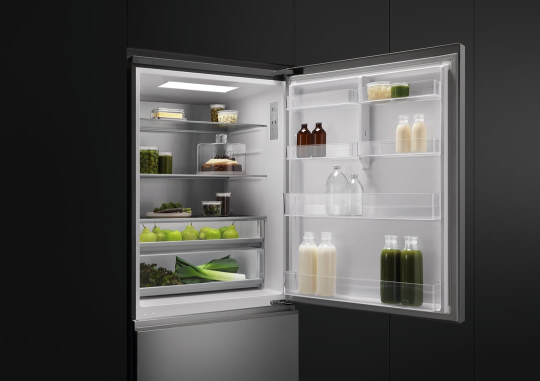 Open stainless steel bottom mount fridge filled with food and drinks