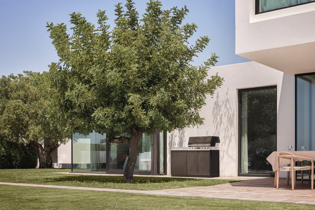Outdoor kitchen BBQ module on a patio next to a modern house