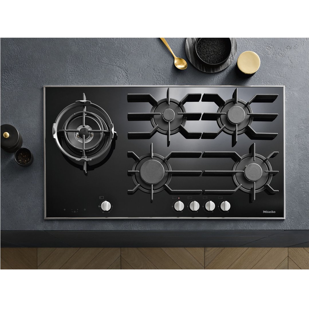Black 5-burner gas cooktop with controls, on a dark countertop with accessories