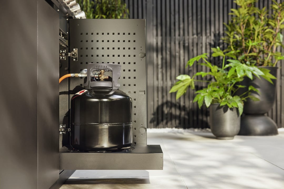 BBQ gas bottle storage system with a gas bottle inside, in an outdoor setting