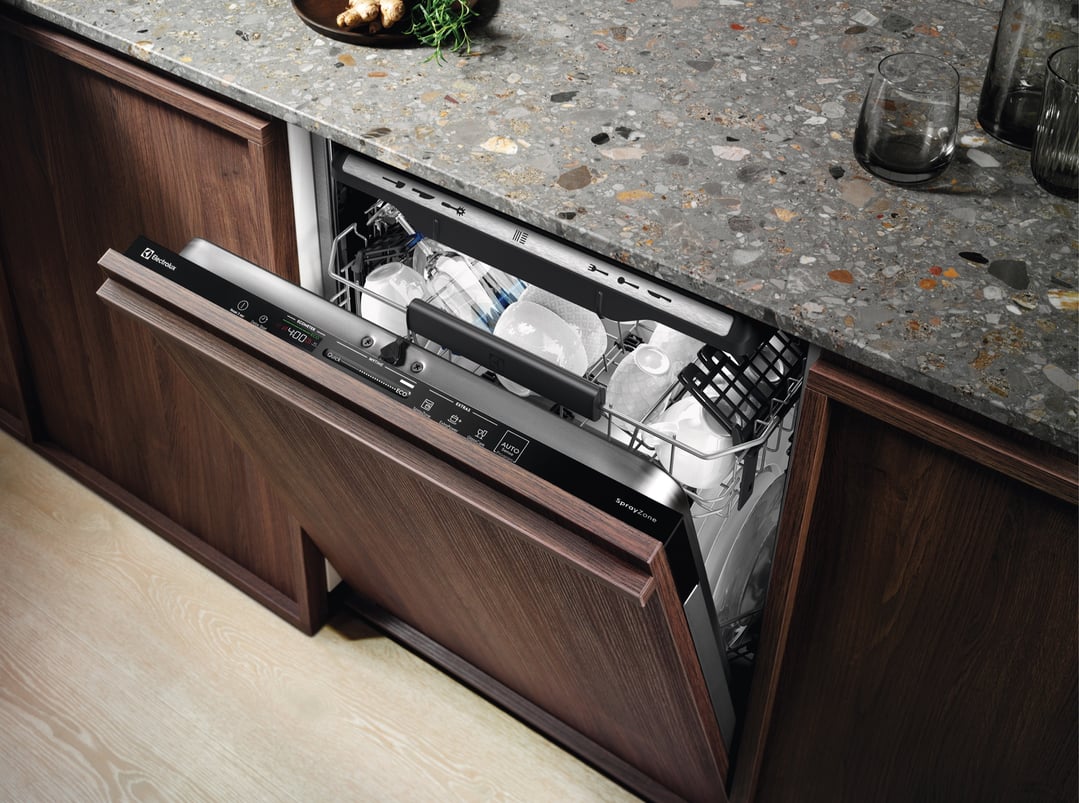 Open integrated dishwasher with dishes inside in a modern kitchen
