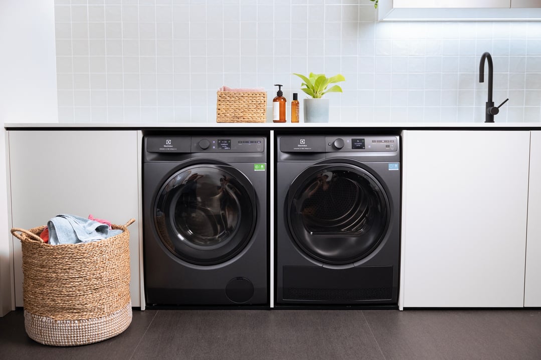 Two dark onyx laundry appliances in a styled laundry room with sink