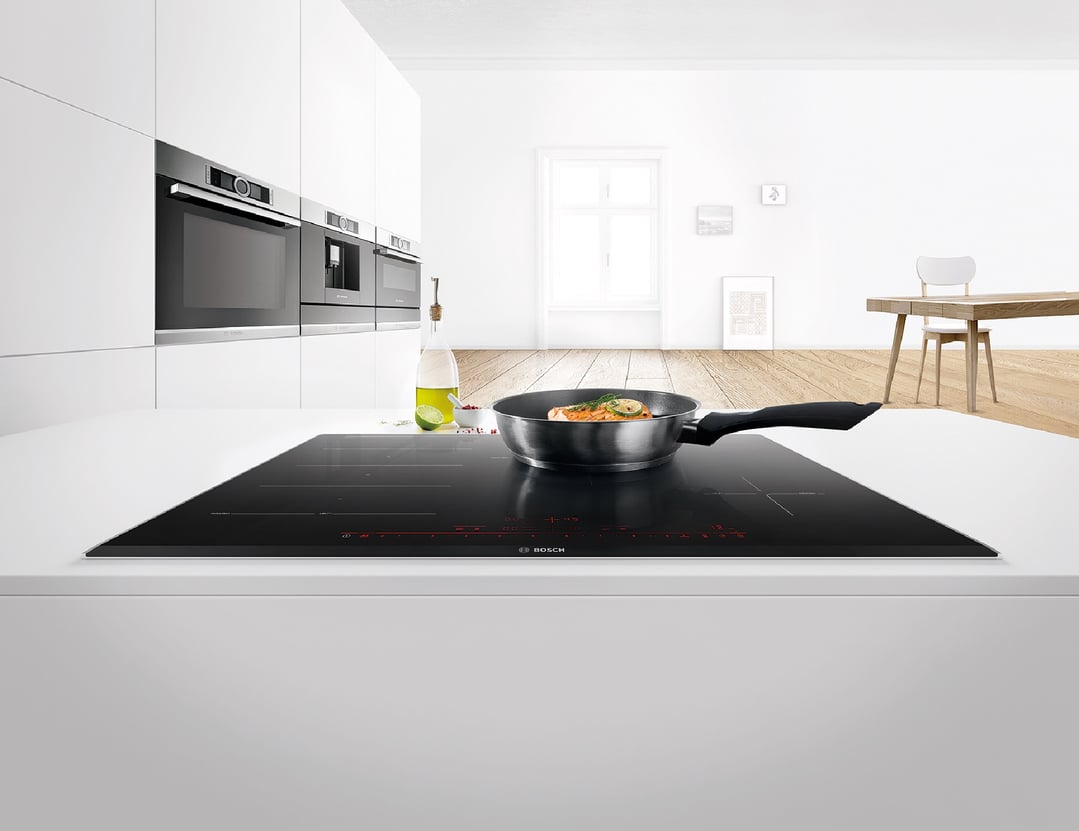 Black Bosch induction cooktop with a pan of salmon in a modern kitchen