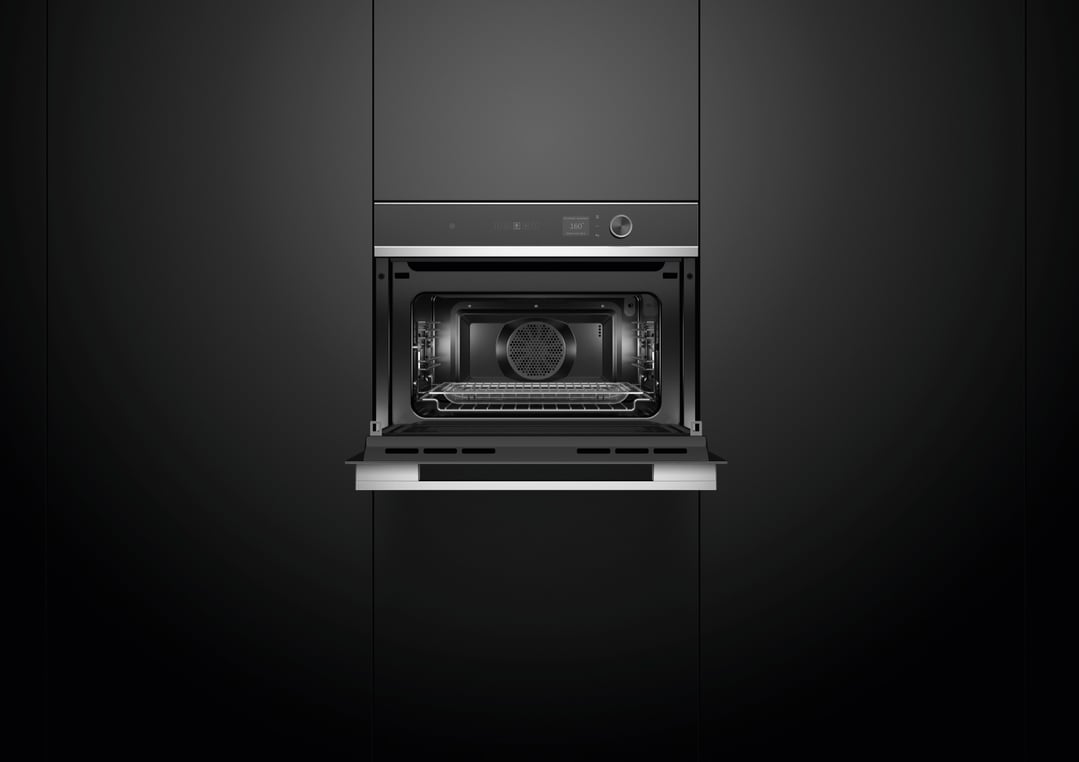 Compact combi-microwave oven with the door open, built into dark cabinetry