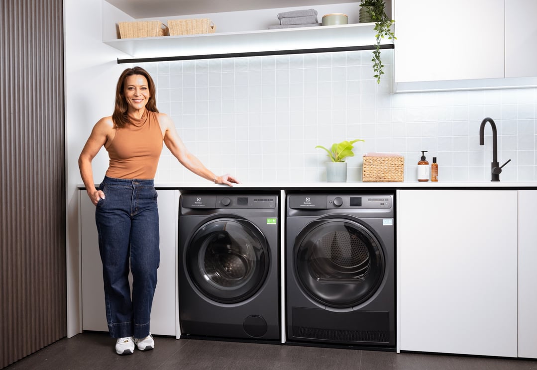 Woman standing next to a washing machine and a dryer in a modern laundry room