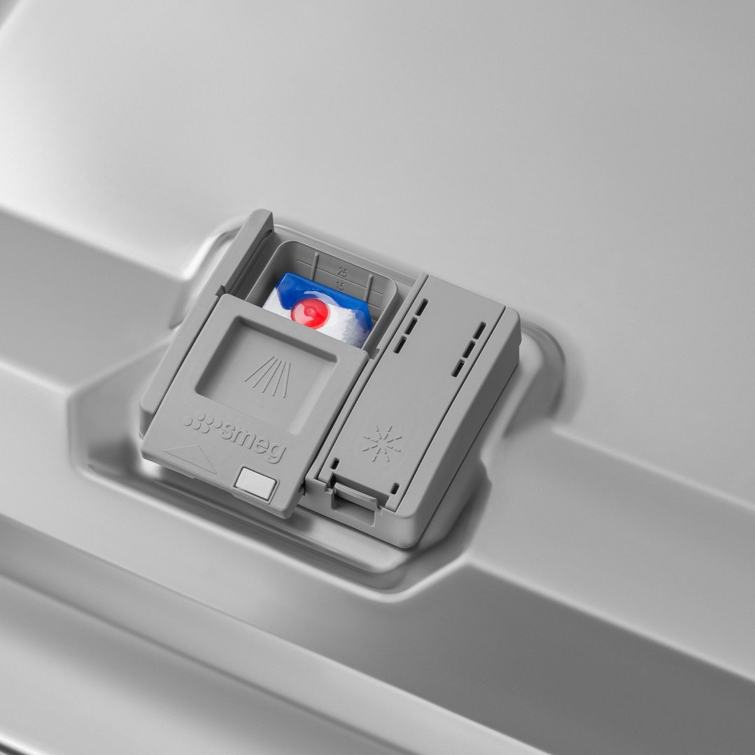 Close-up of a dishwasher detergent dispenser with a detergent pod inside