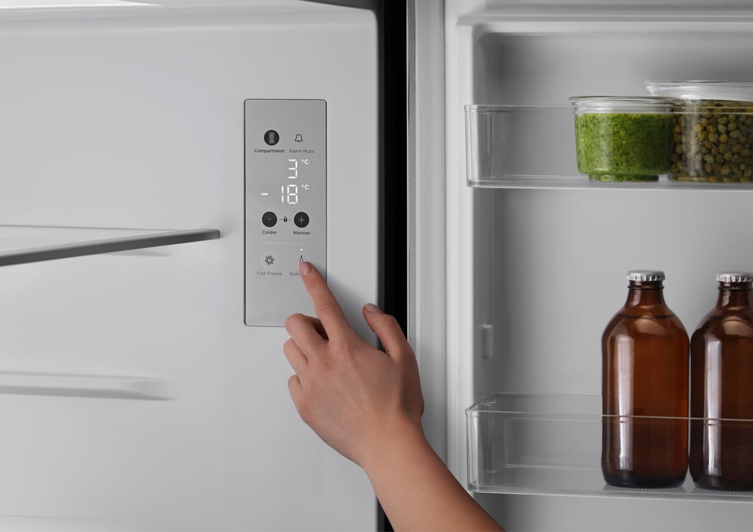A hand adjusting the temperature controls on a Fisher & Paykel fridge