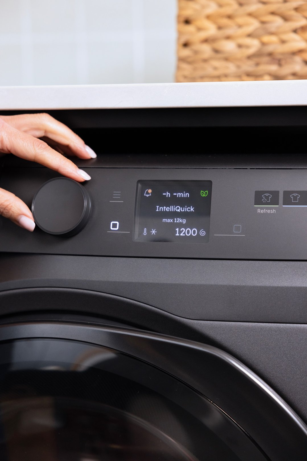 Hand adjusting the settings on a dark onyx heat pump dryer