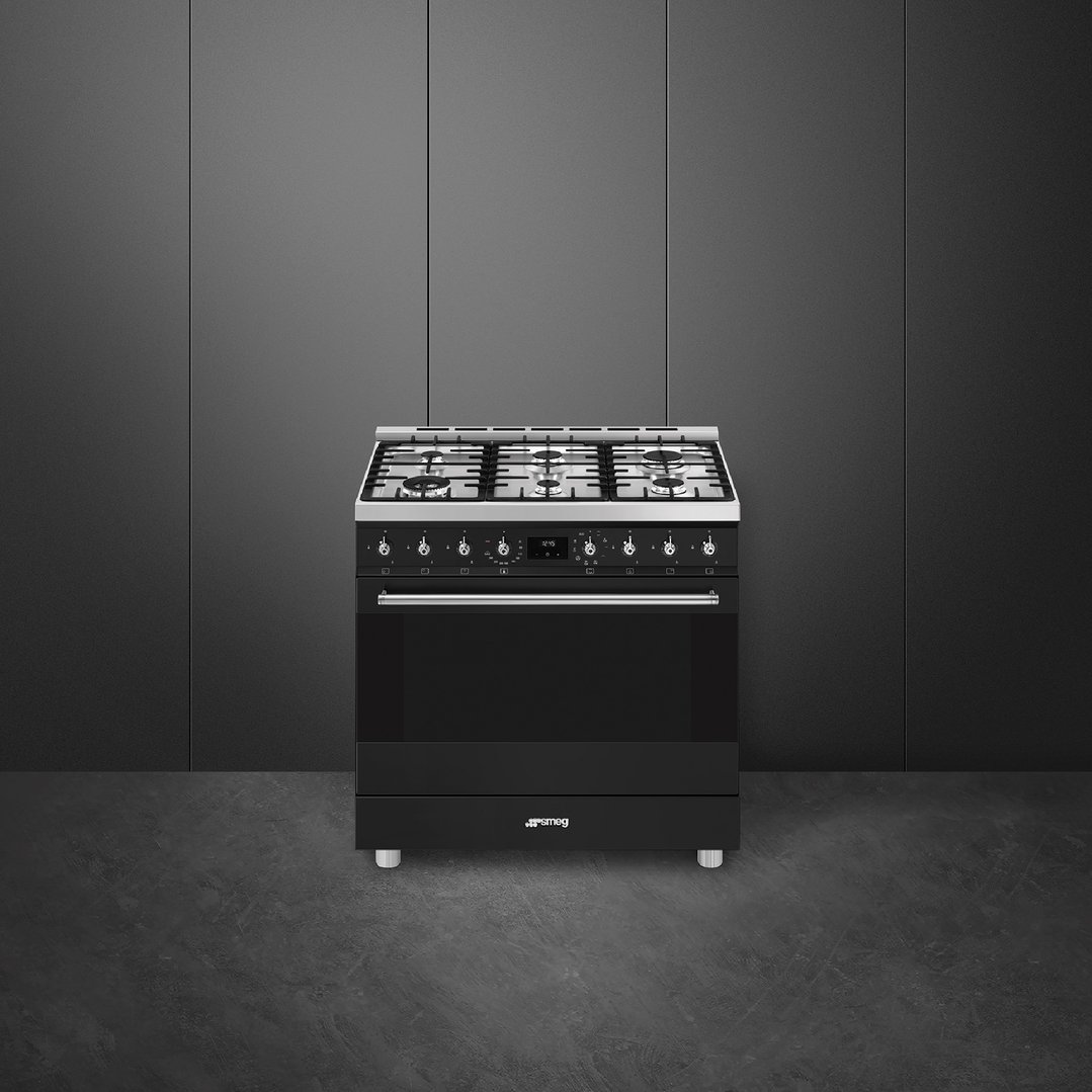 Black freestanding oven with six burners in a dark grey room