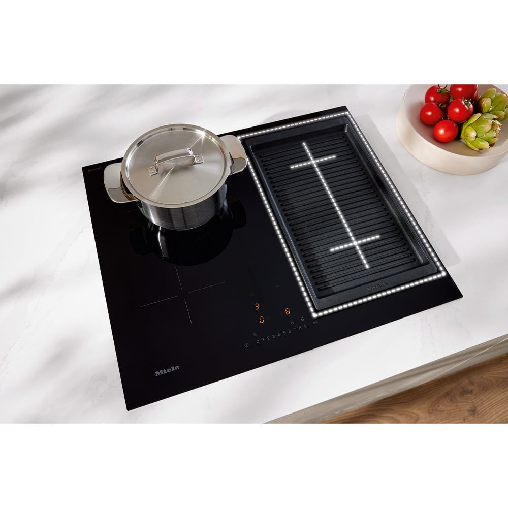 Black induction cooktop with a pot and a grill pan on a white countertop