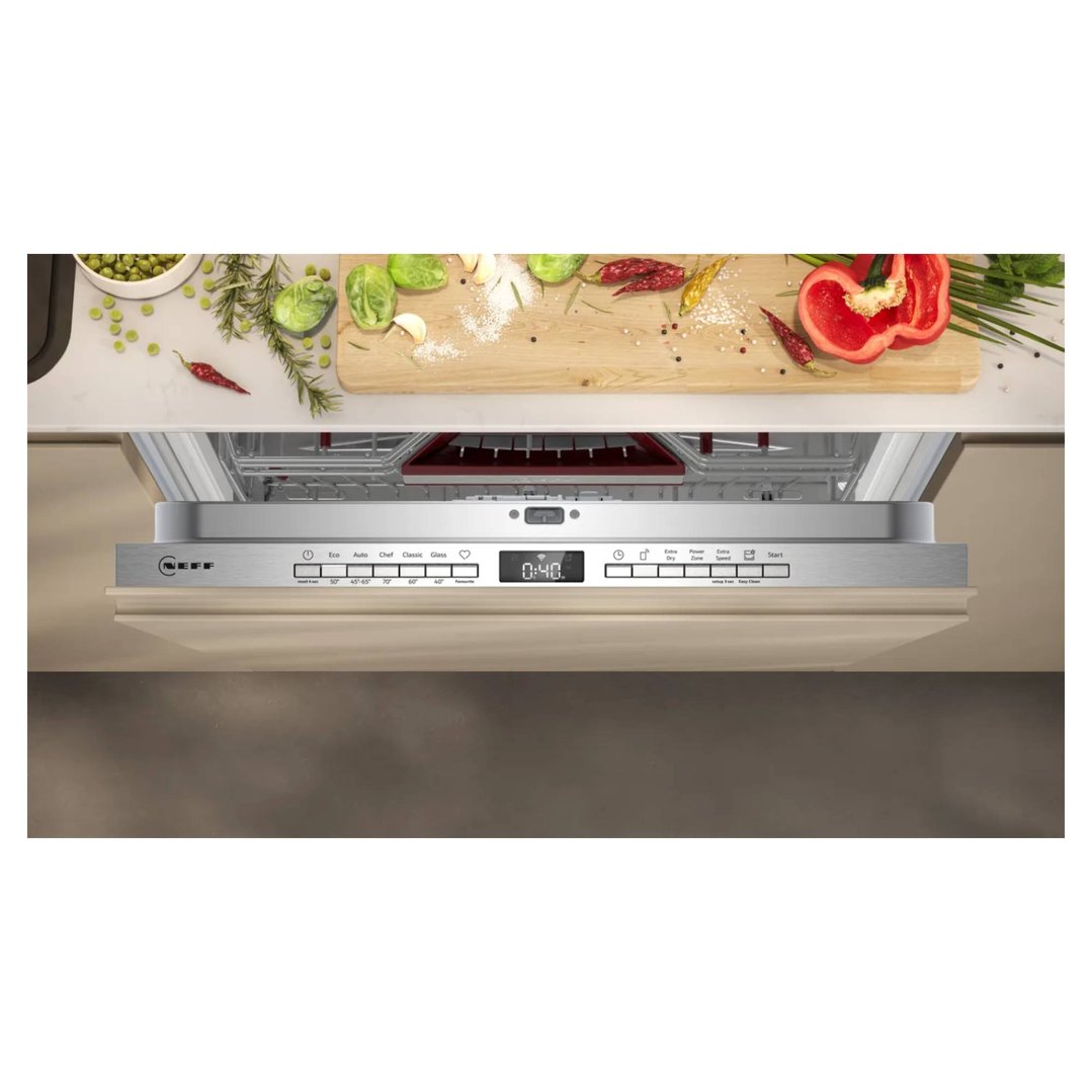 Dishwasher with control panel open, surrounded by fresh vegetables and spices