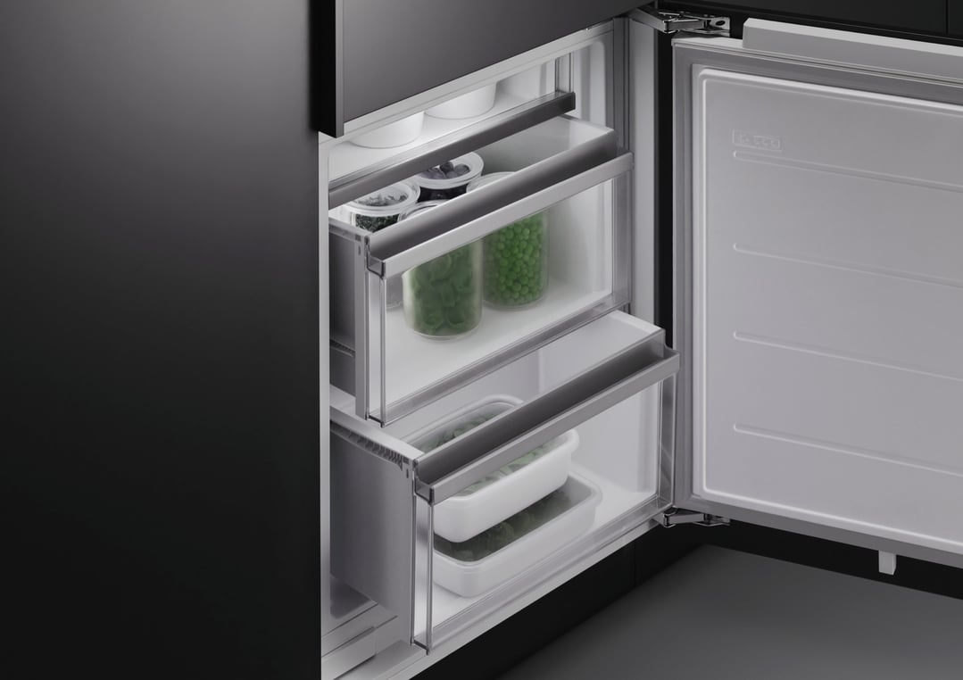 Open integrated refrigerator freezer showing frozen vegetables in clear containers