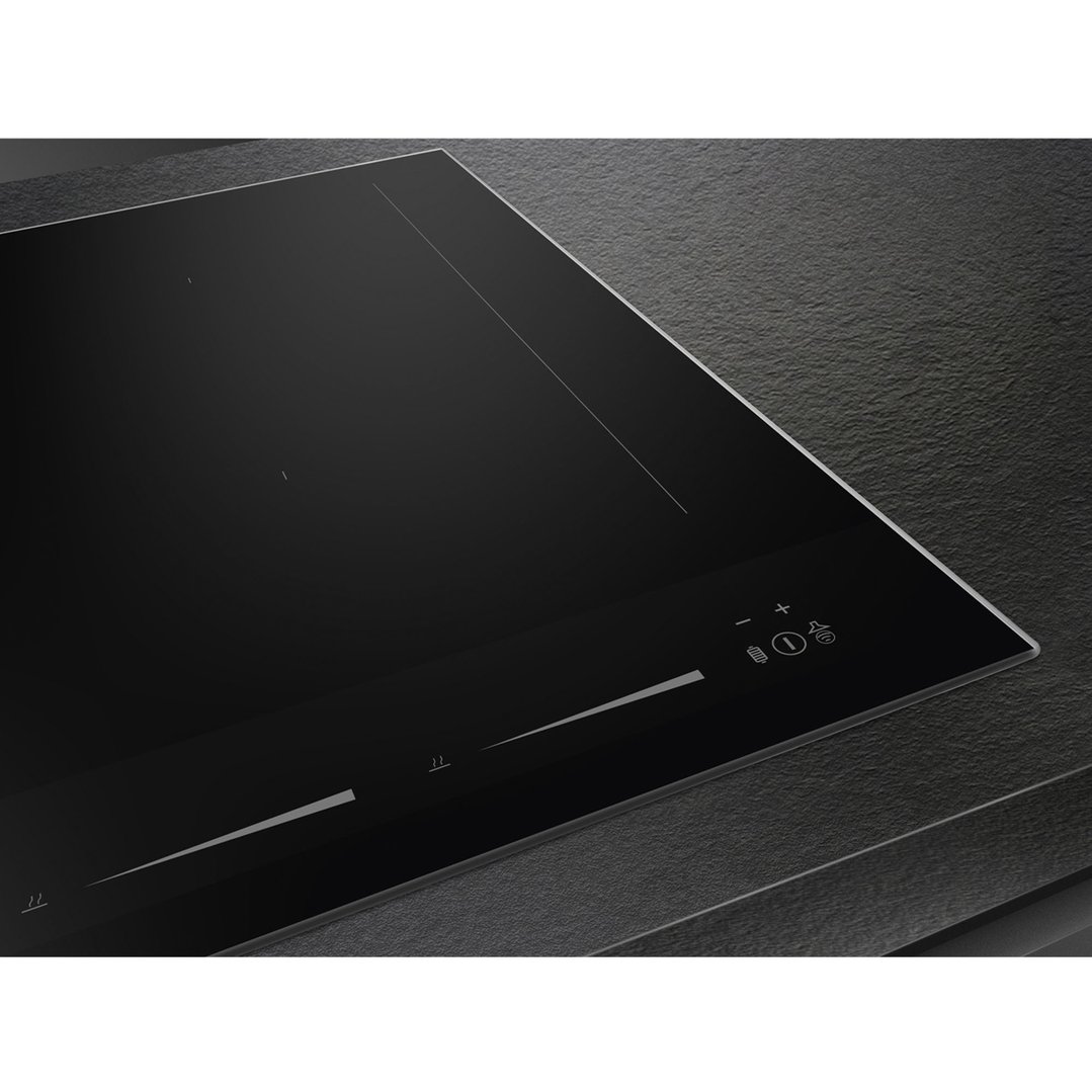 Close-up of a black induction cooktop with controls on a dark countertop