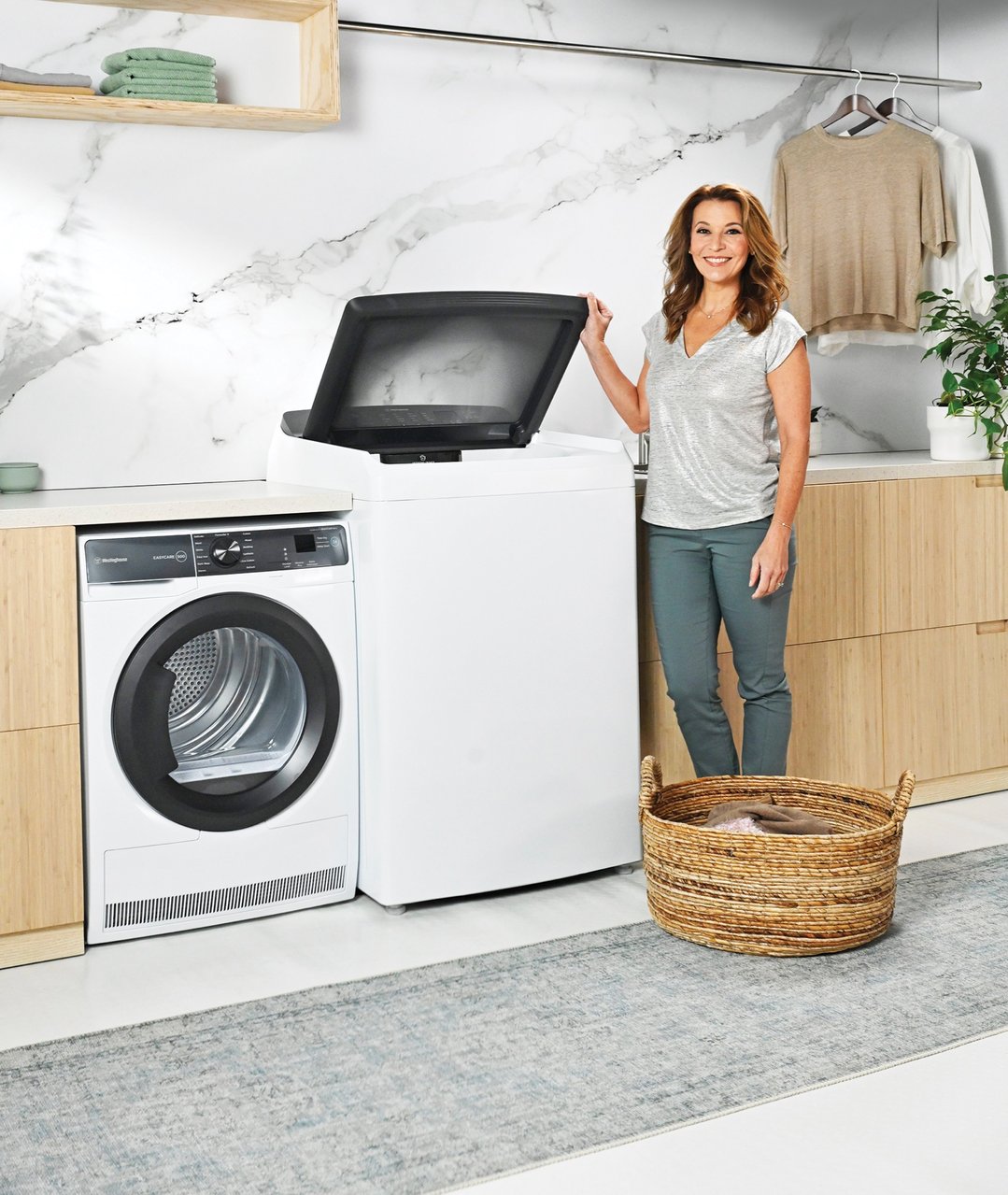 Woman smiling while loading laundry into a top load washing machine