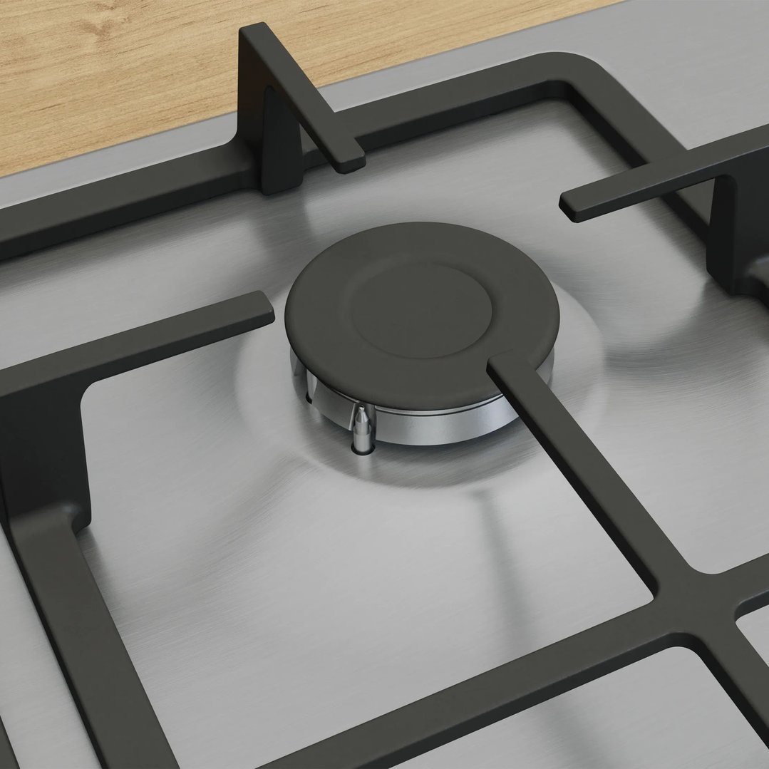 Close up of a gas cooktop with black grates and a wooden background