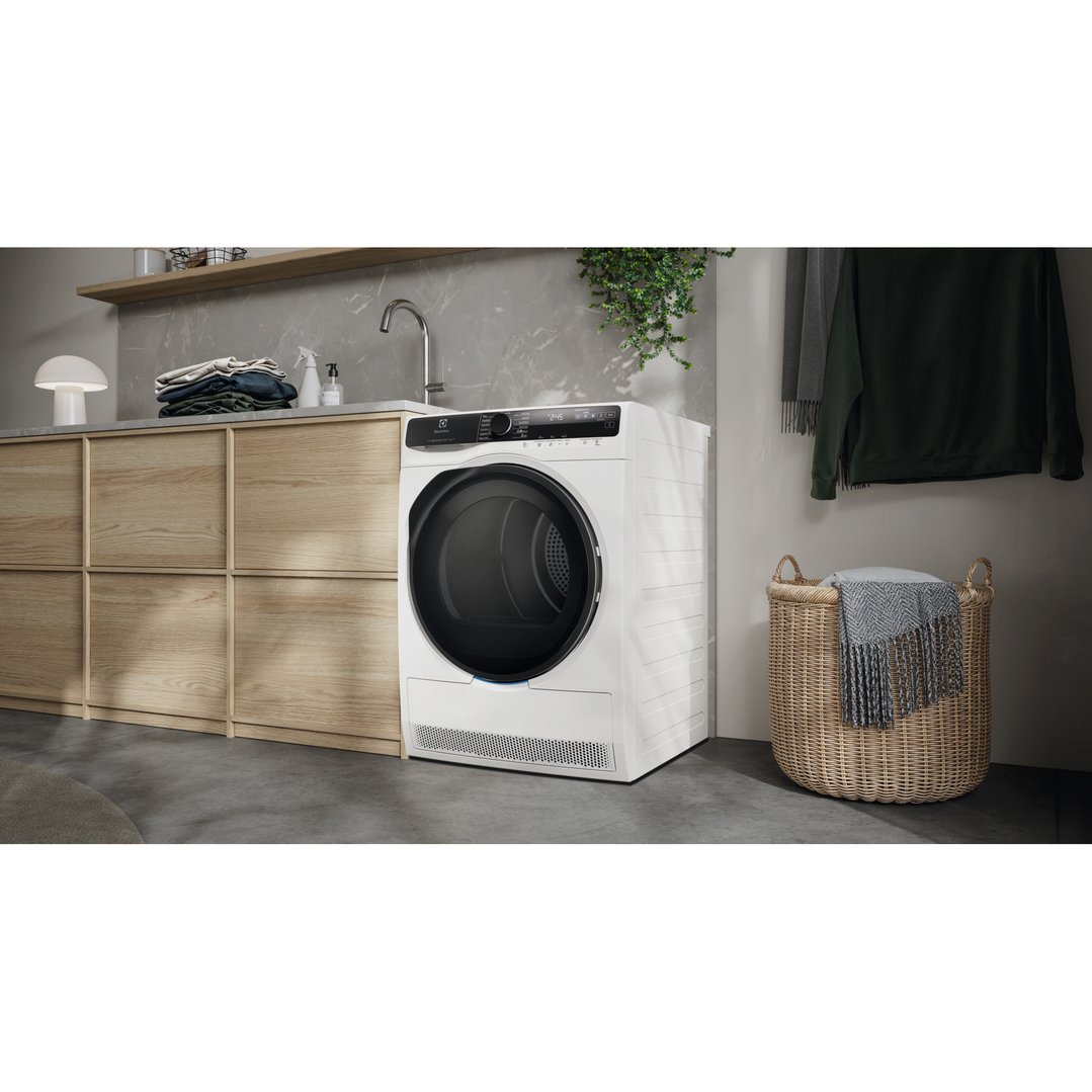 White Electrolux dryer in a modern laundry room with wooden cabinets