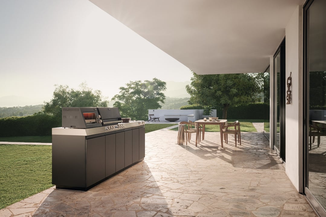 Outdoor kitchen BBQ on a patio with a dining table and chairs