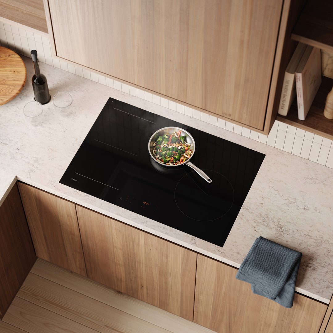 Overhead view of an ASKO induction cooktop with a pan of vegetables