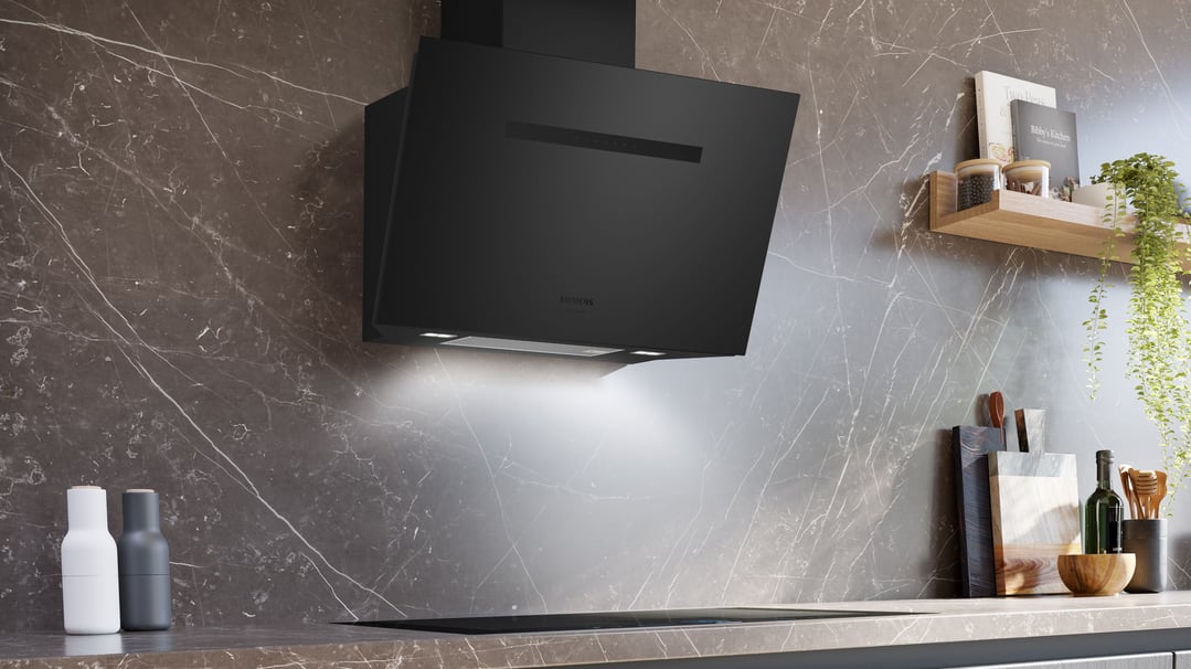 Black inclined canopy rangehood mounted on a dark marble wall in a modern kitchen