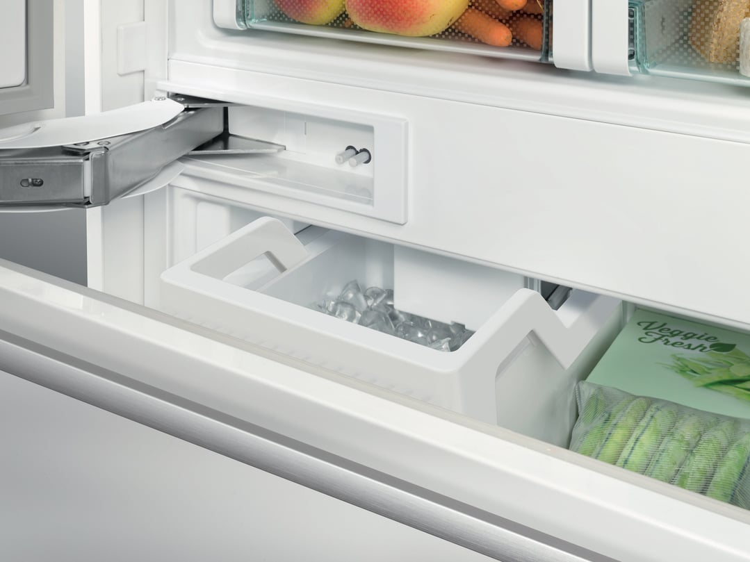 Close-up of the interior of a fridge with ice maker and vegetable drawer