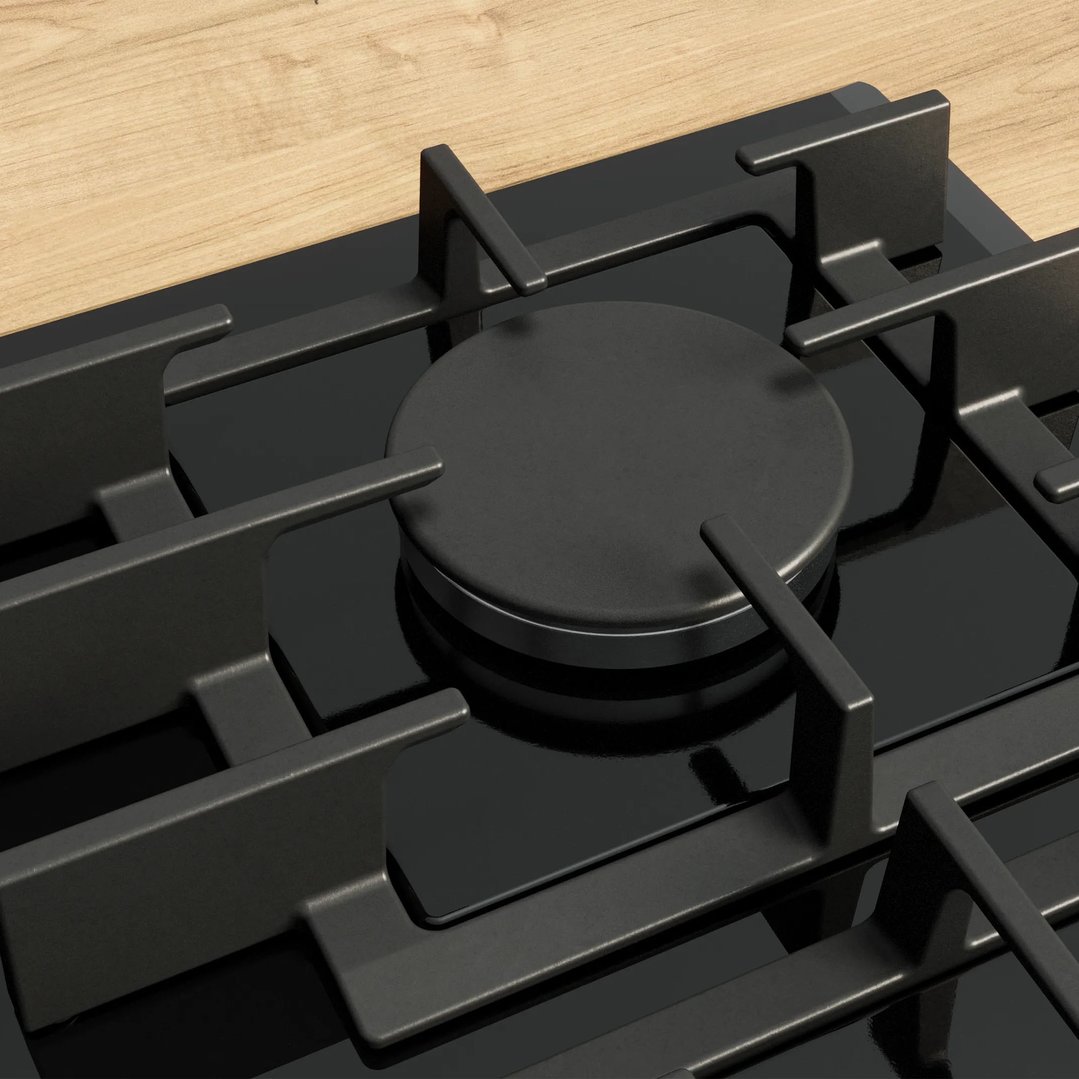 Close up of a black gas cooktop with grates on a wooden countertop