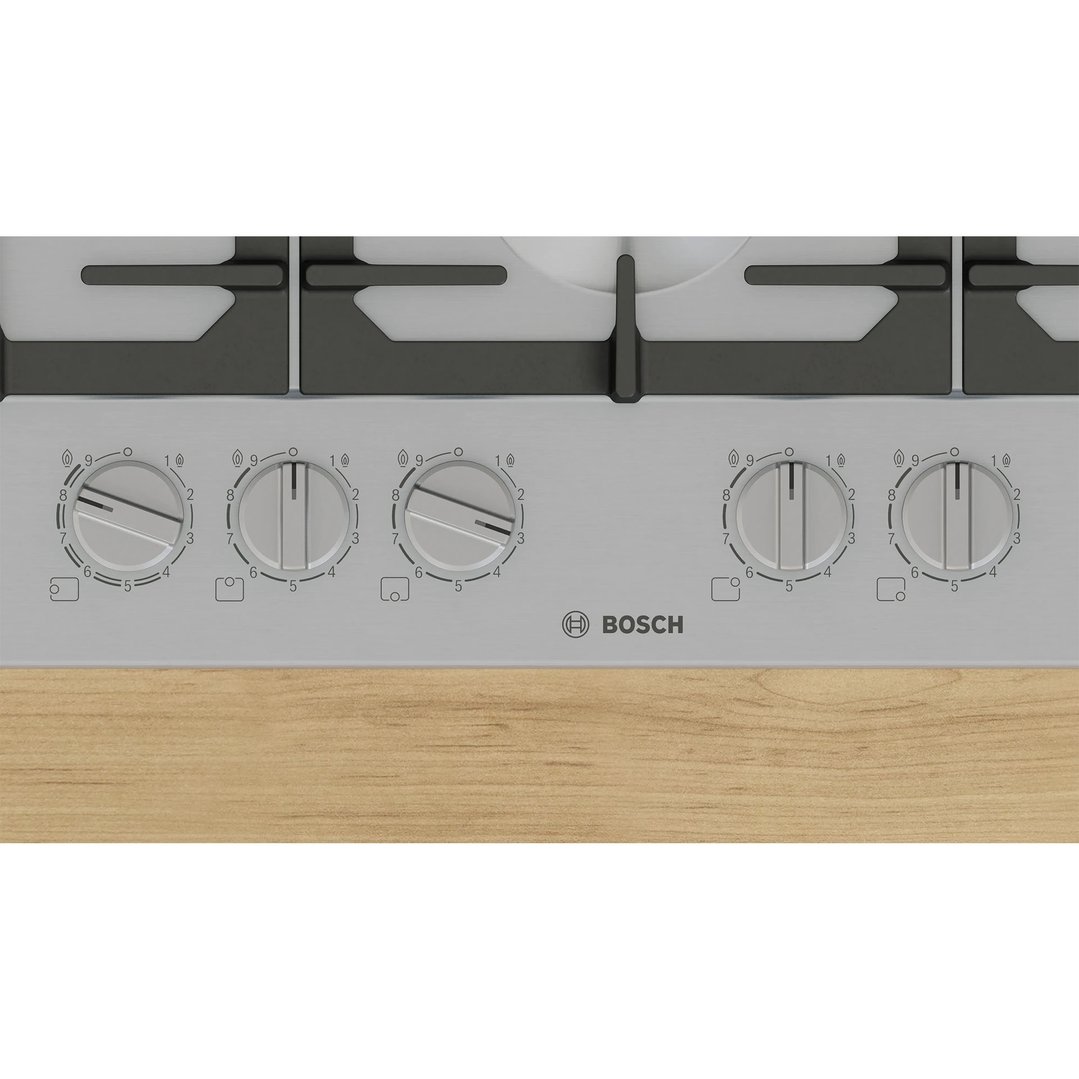 Close up of a Bosch gas cooktop with control knobs on a wooden surface