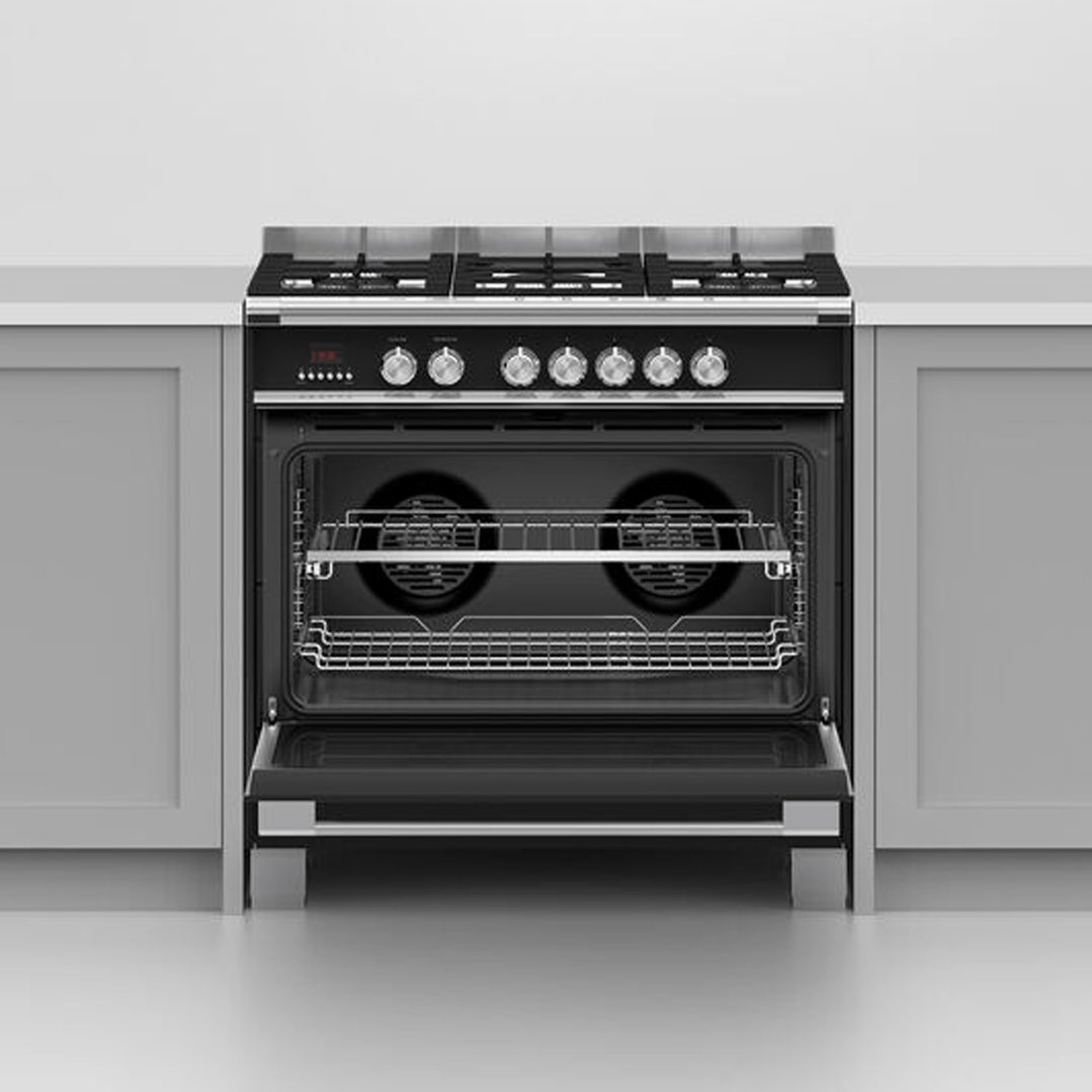 Black freestanding dual fuel cooker with oven door open in a kitchen setting