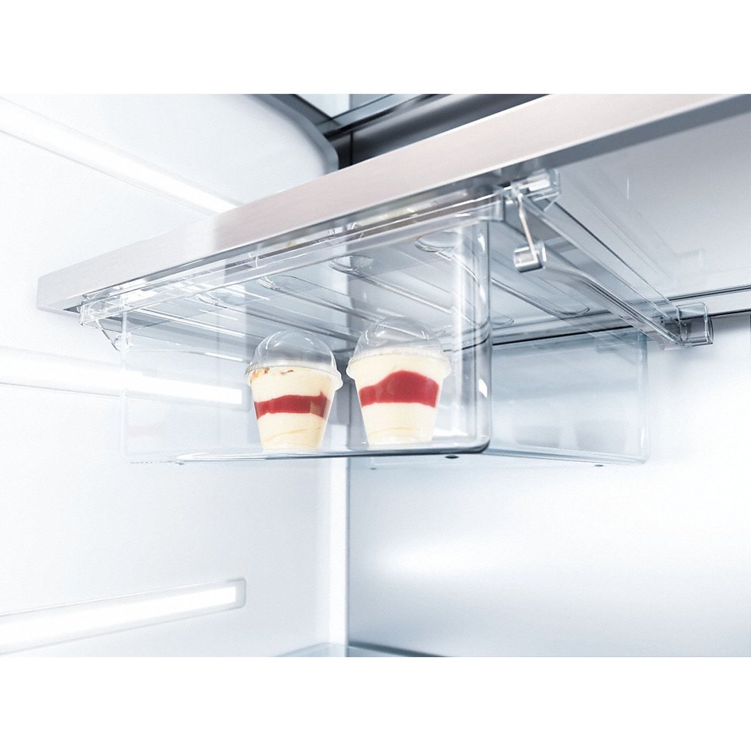 Two desserts in clear containers in a fridge's clear storage drawer