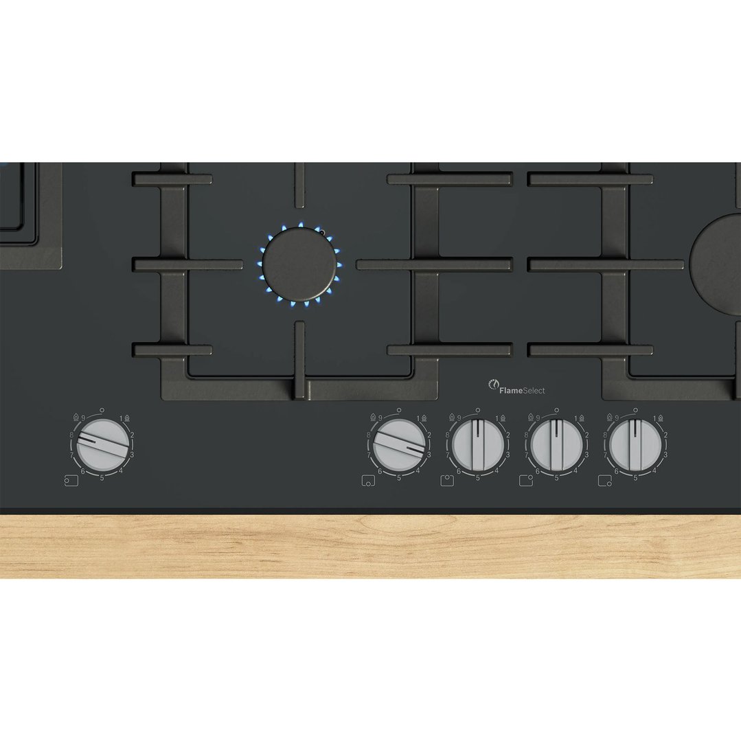 Black gas cooktop with five burners and control knobs, one burner lit