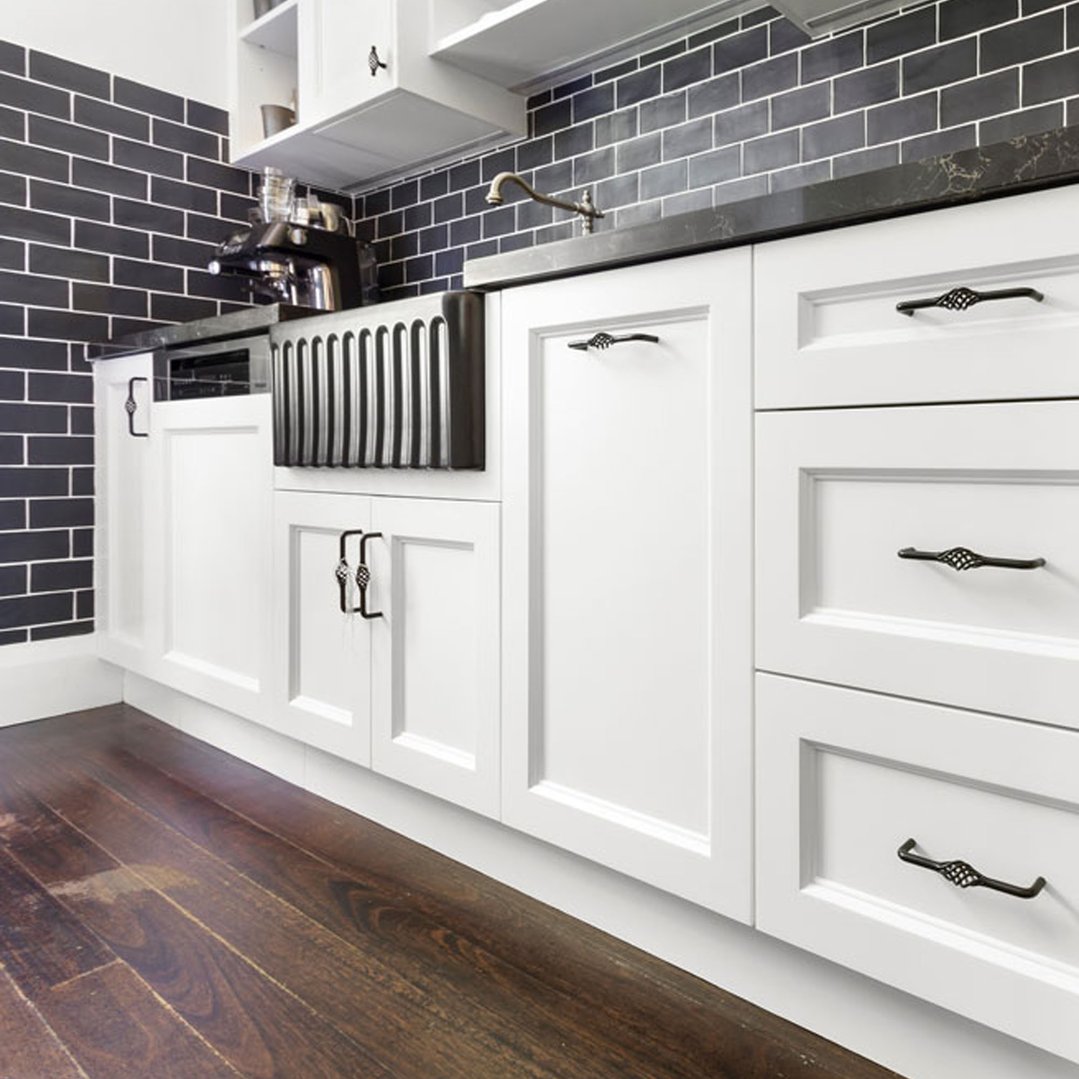 Matte black fireclay butler sink in a modern kitchen with white cabinets